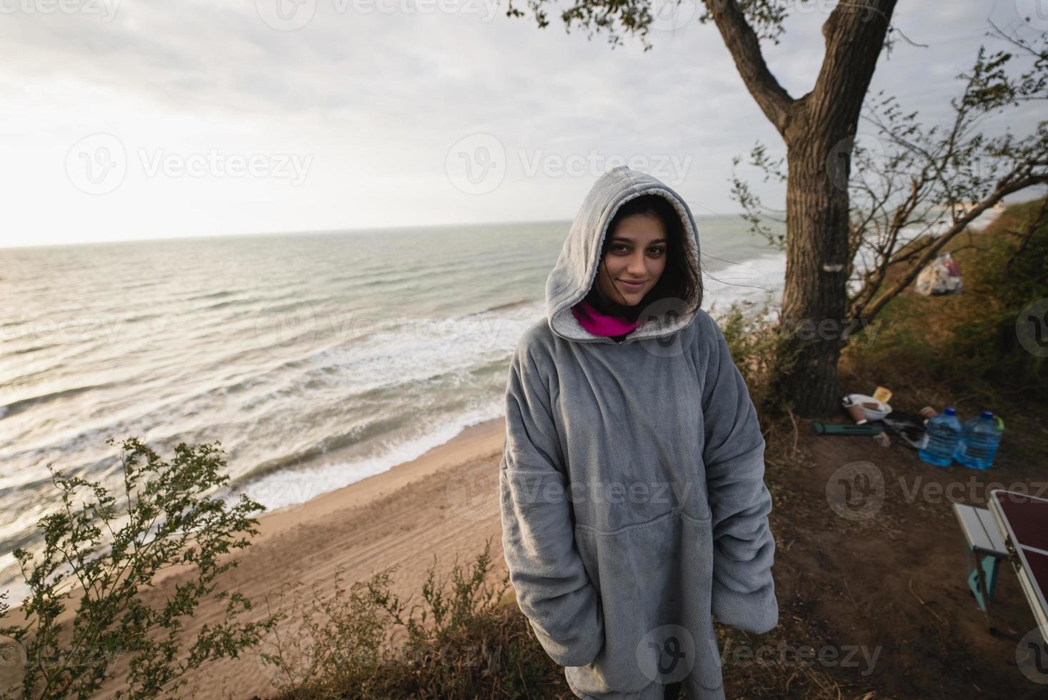 ung kvinna på kall höst havsstrand Framställ på kamera foto