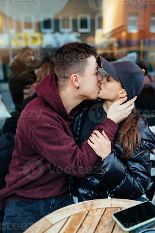 kille och en flicka är kissing på en tabell i en utomhus- Kafé. foto