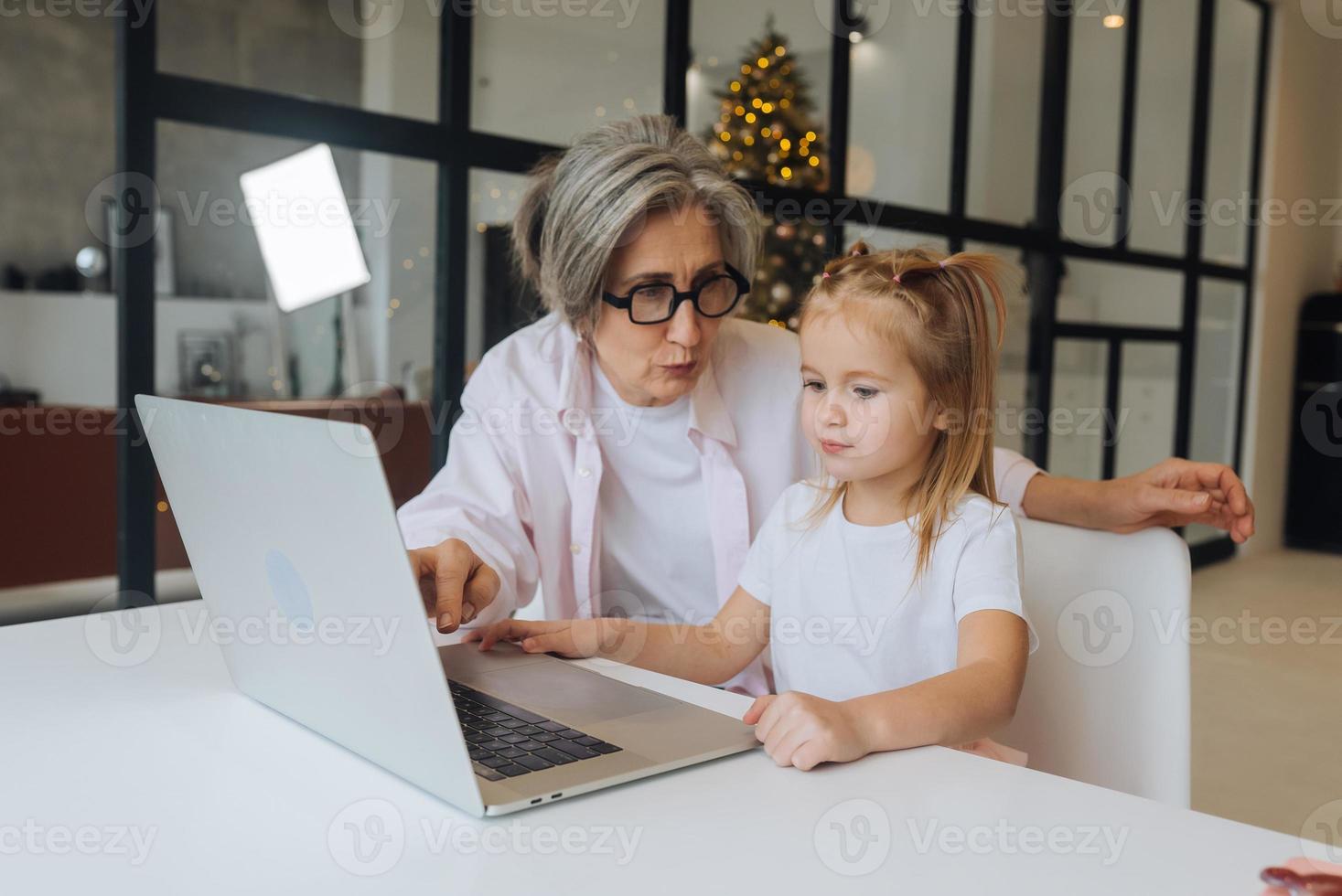 barn och mormor ser på de kamera med bärbar dator foto