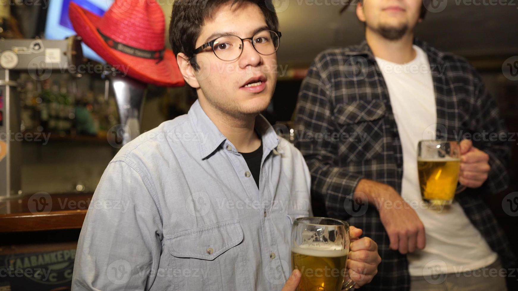 kille med en öl i en bar med vänner på en lördag natt foto