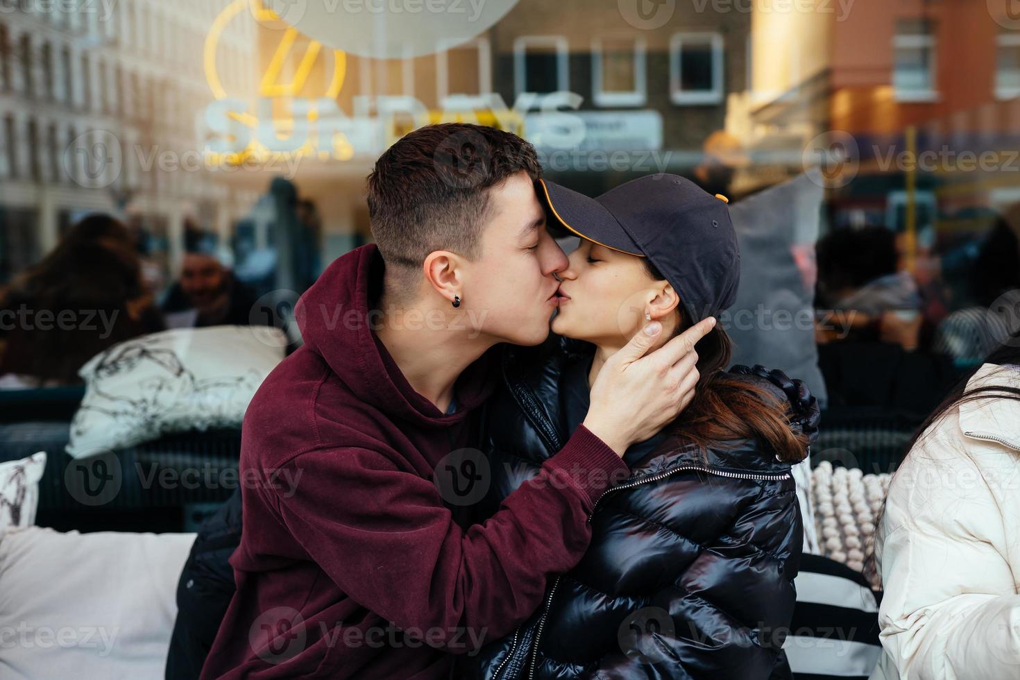kille och en flicka är kissing på en tabell i en utomhus- Kafé. foto
