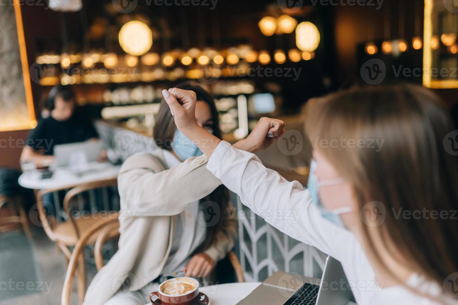 medarbetare i skyddande masker ger hög fem med armbågar. foto