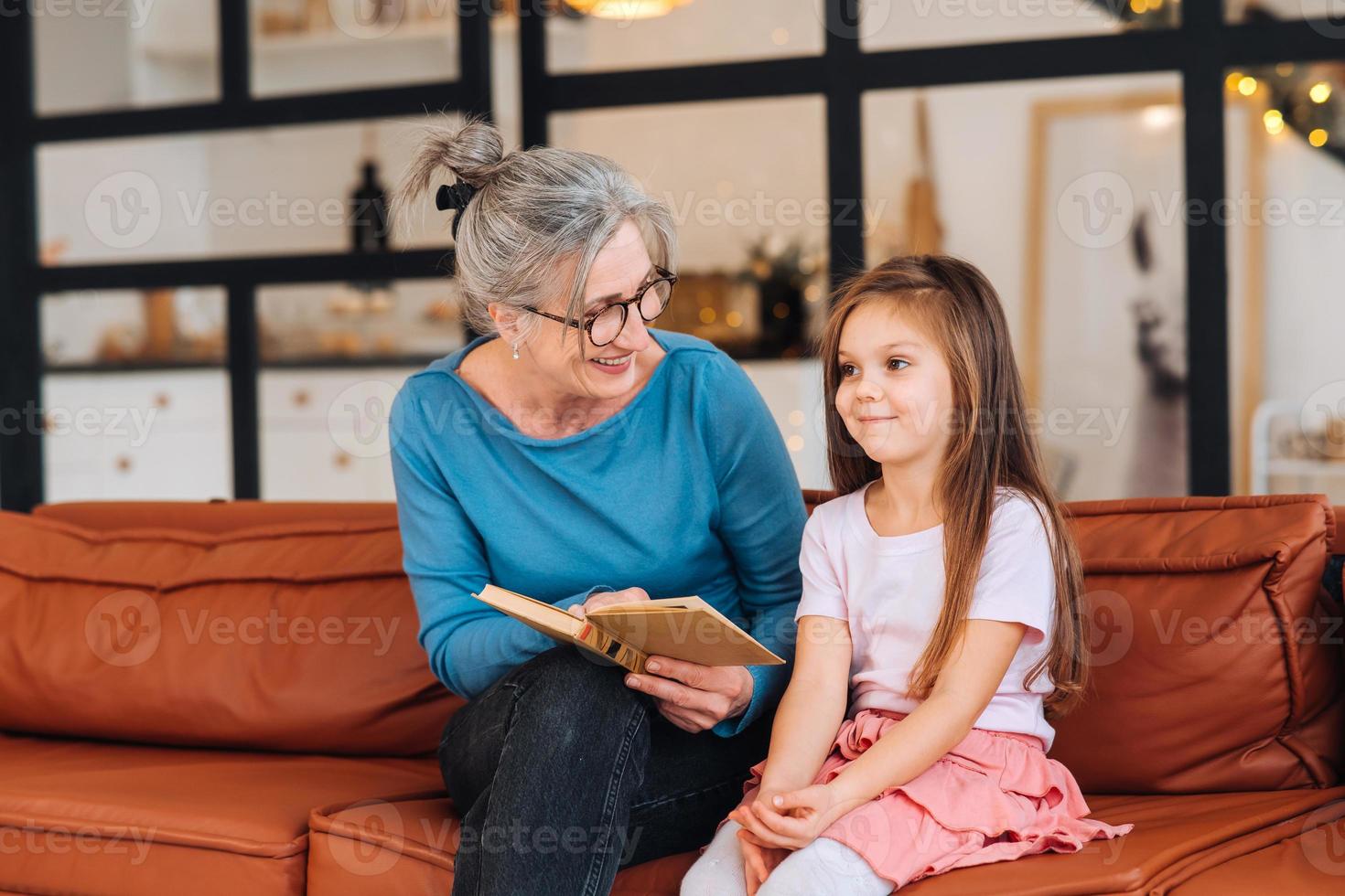 trevlig äldre kvinna mormor läsning berättelse till barnbarn. foto