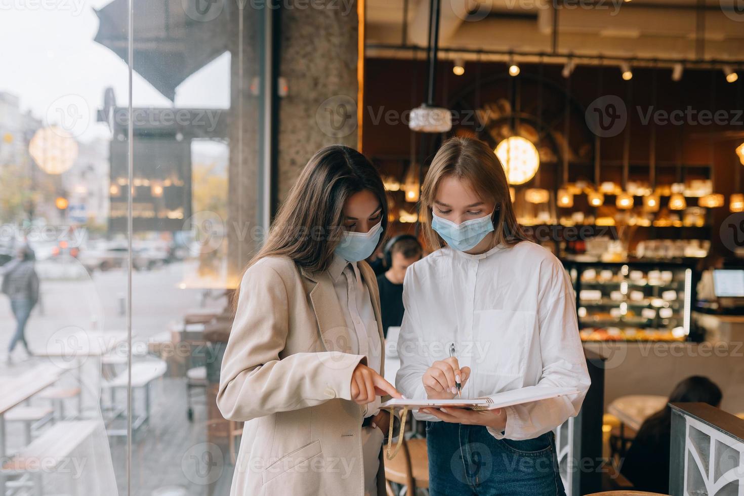 två affärskvinna med deras ansikte masker debatterande annorlunda visningar på arbete foto