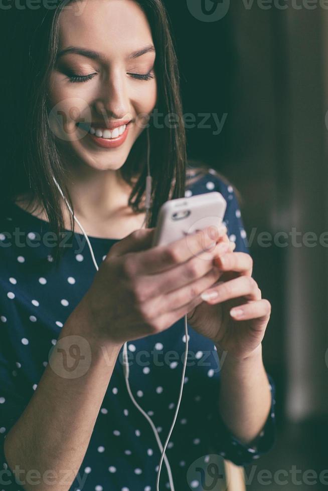 vacker flicka lyssnar på musik i telefon med hörlurar foto