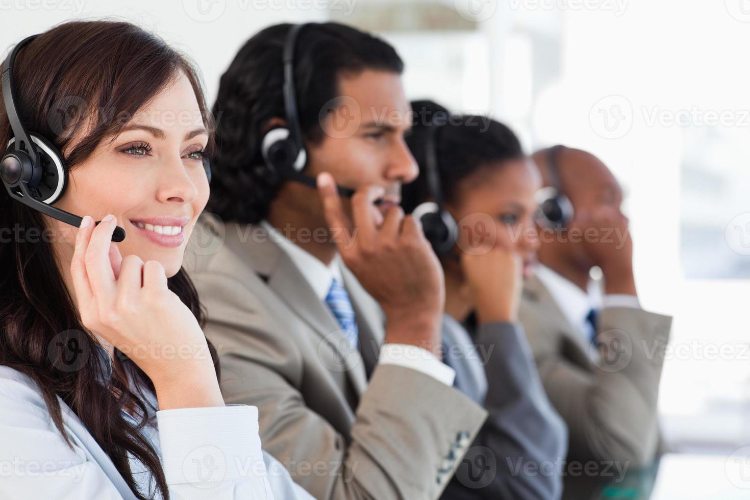 leende anställd i callcenter som arbetar medan hon åtföljs av hennes team foto