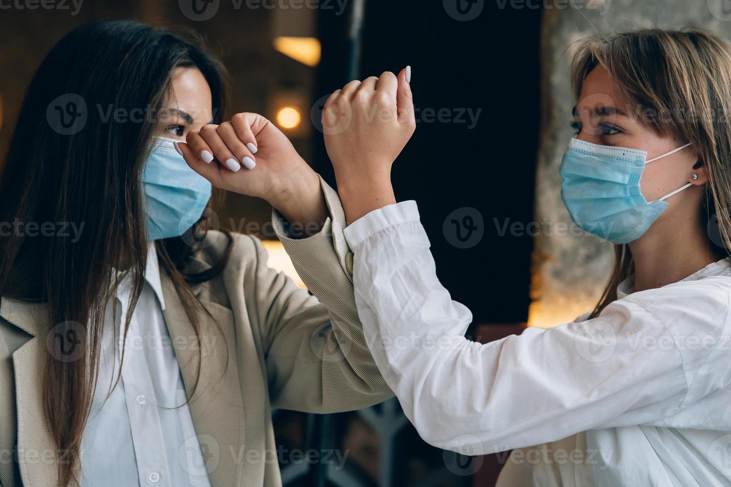 medarbetare i skyddande masker ger hög fem med armbågar. foto