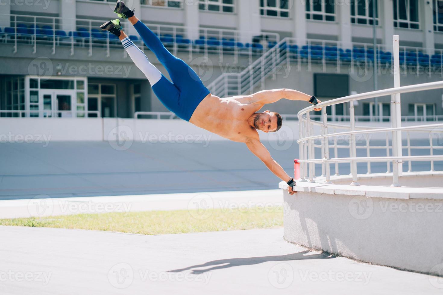 ung atletisk man utför gymnastiska element - mänsklig flagga. foto