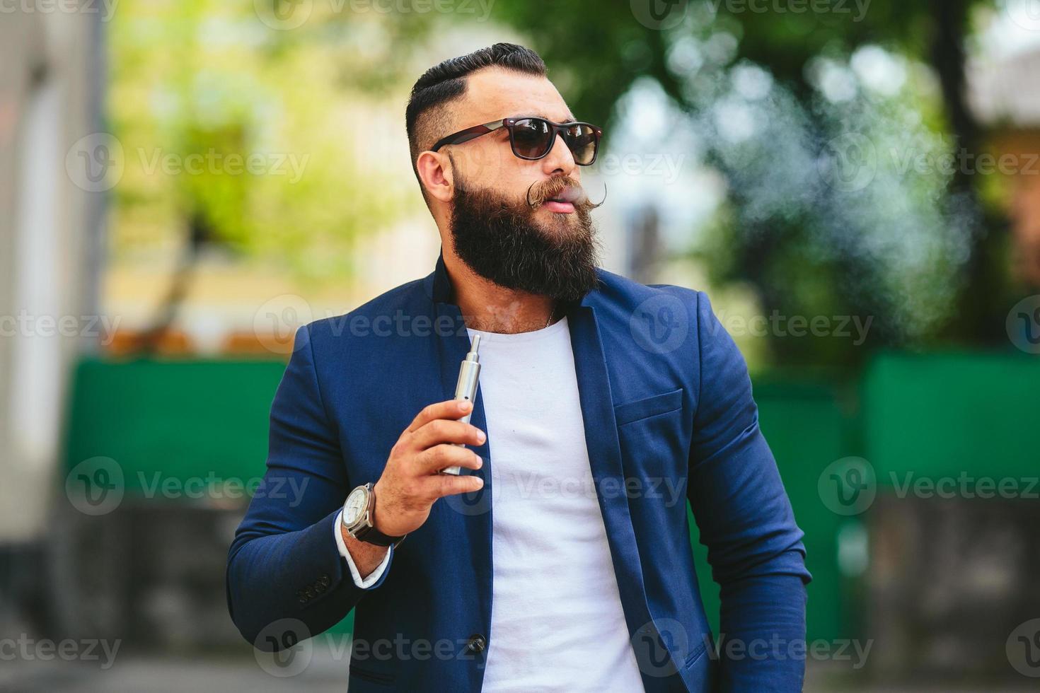 man med ett skägg röker elektronisk cigarett foto
