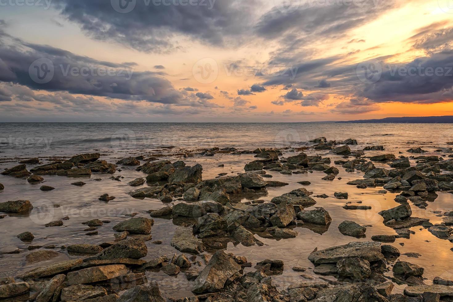 sten strand på solnedgång. skymning hav och himmel. dramatisk himmel och moln. natur landskap. foto