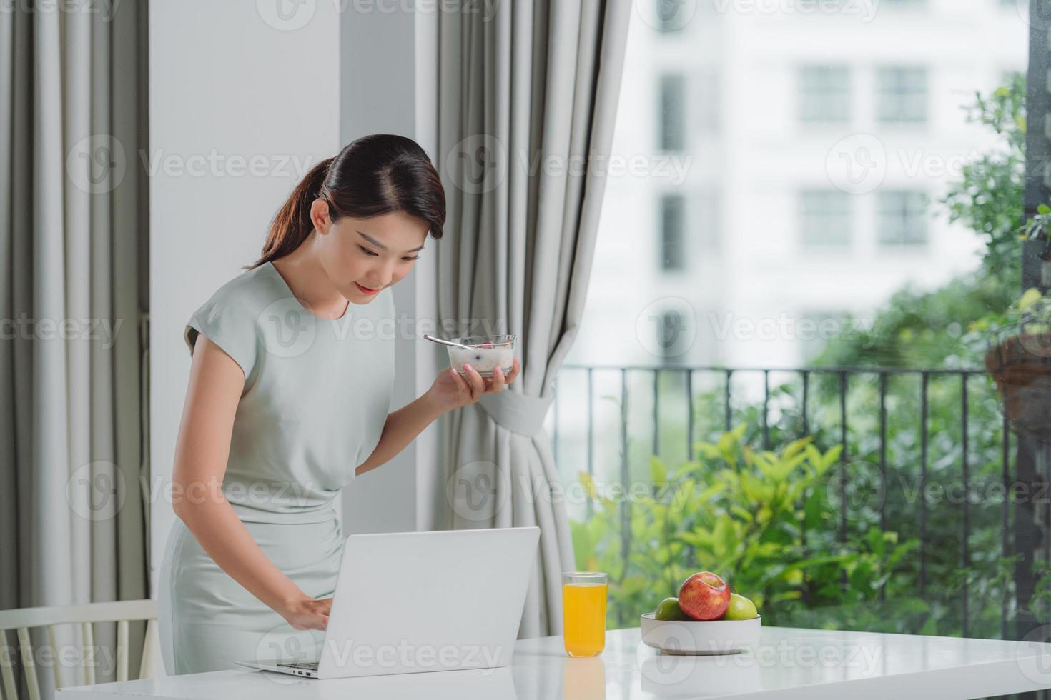 kvinna äter frukost och upptagen arbetssätt på Hem foto