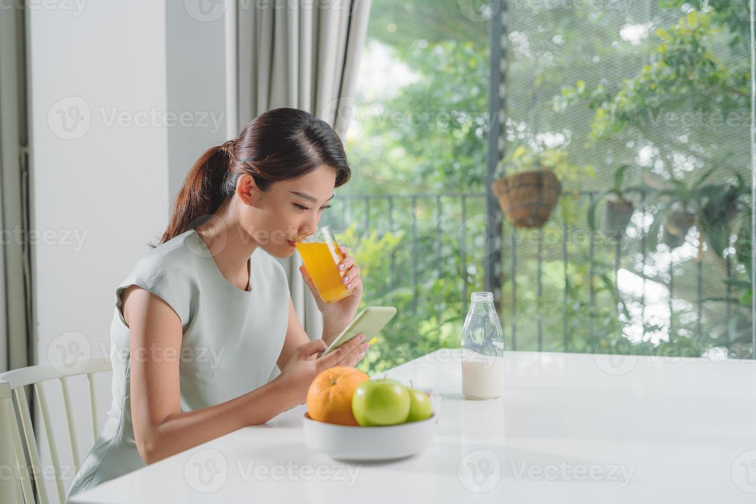 de flicka har en friska frukost på eleganta mysigt Hem på de morgon- medan kontroll henne e-post på mobil. foto