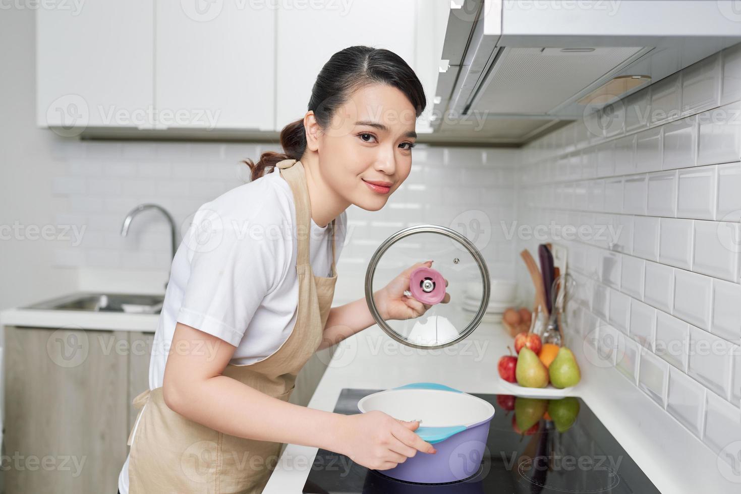 ung kvinna stående förbi de spis i de kök . foto