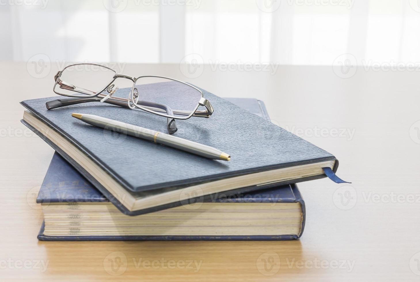 svart bok med glasögon och penna foto