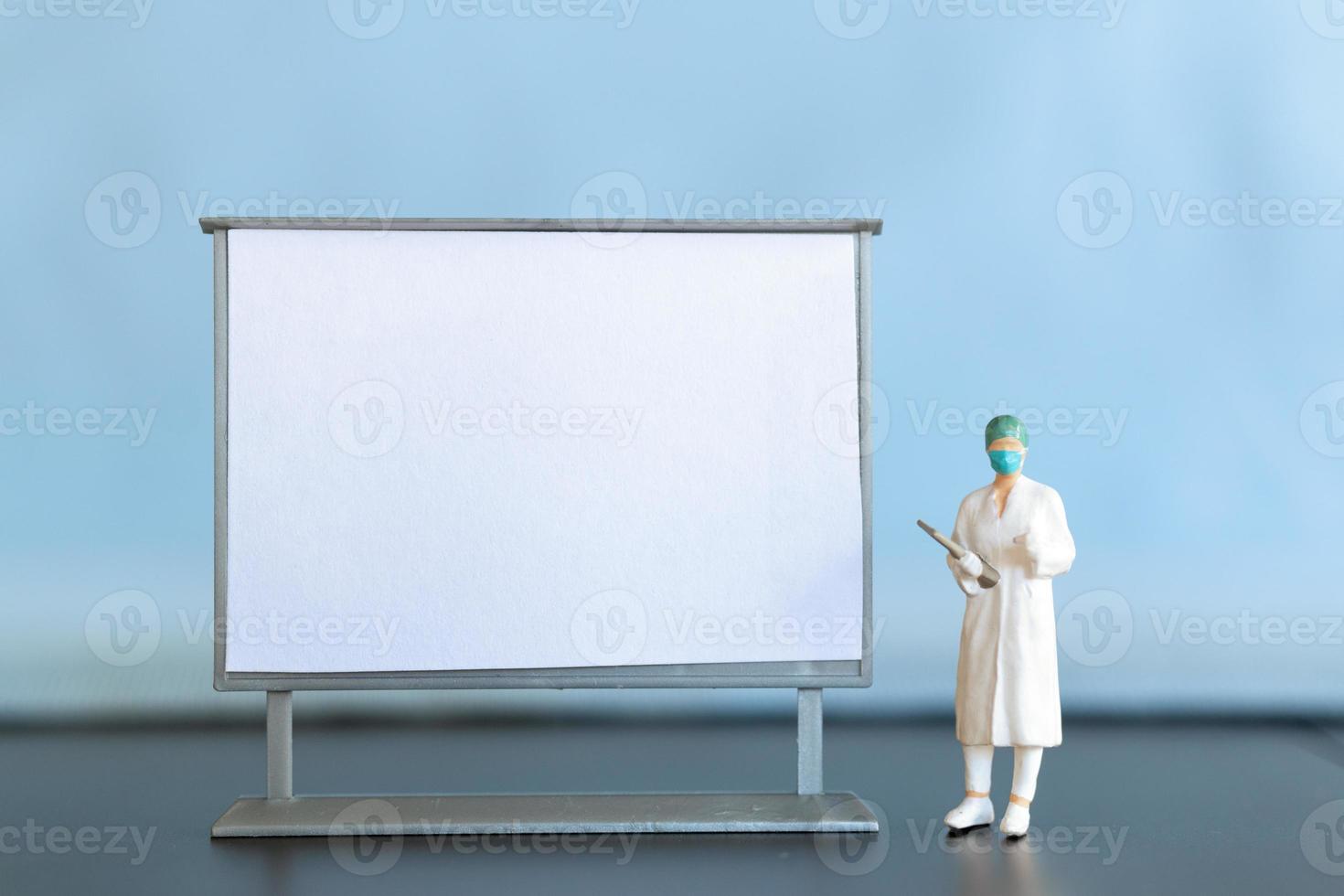 miniatyr- läkare stående med tom vit styrelse foto