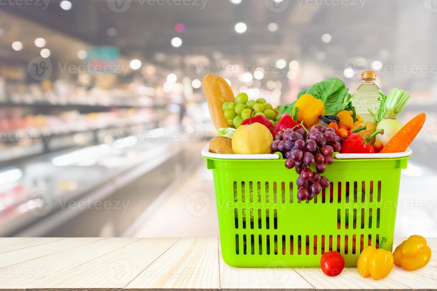 varukorg fylld med frukt och grönsaker på träbord med supermarket livsmedelsbutik suddig oskarp bakgrund med bokeh ljus foto