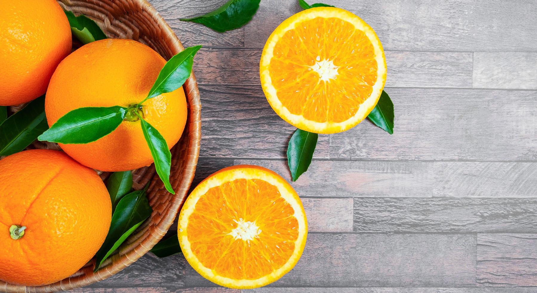 topp se av färsk orange frukt i korgar och halverad orange frukt på de trä- bakgrund. foto