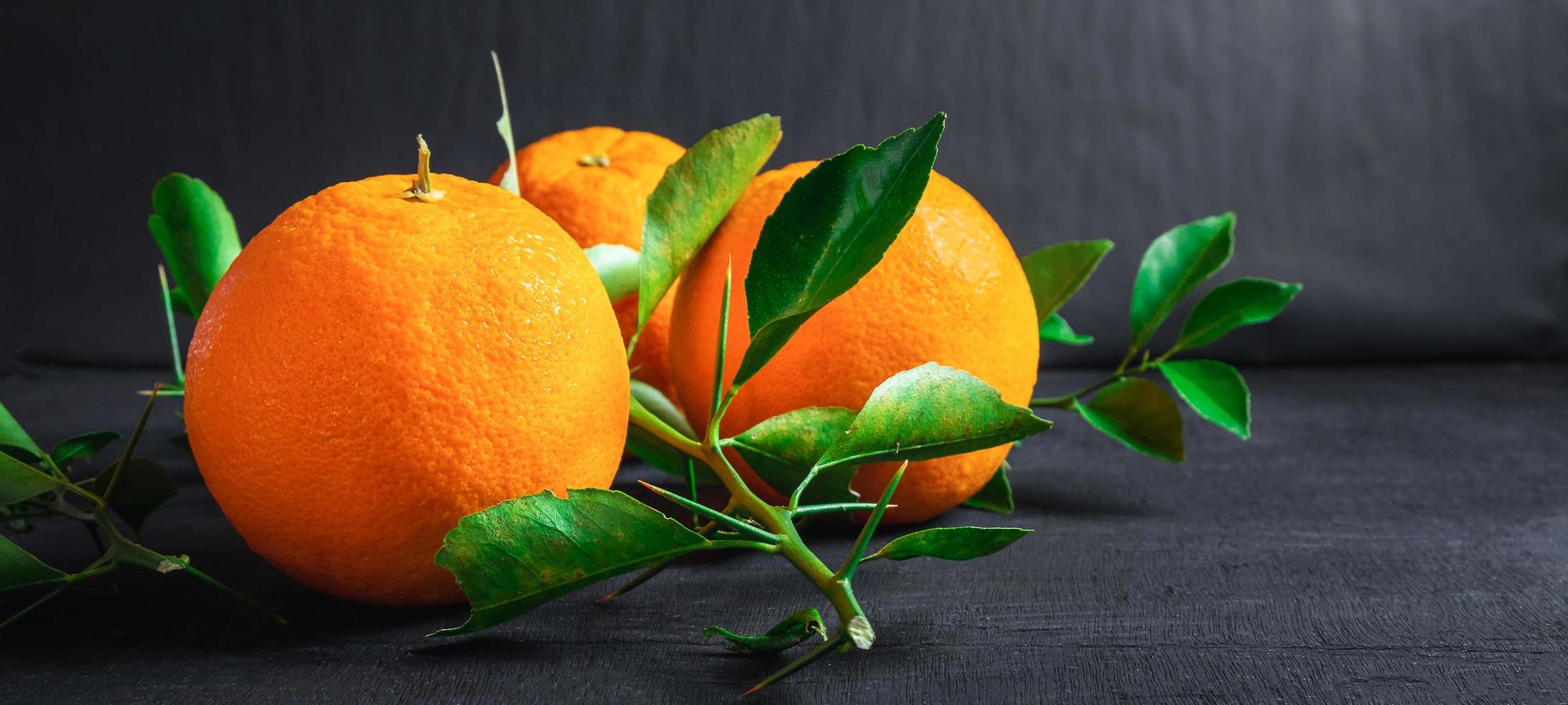 färsk orange och blad på svart bakgrund foto