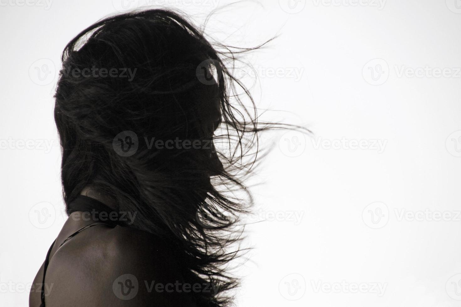 silhuett av en kvinna med lång hår på en blåsigt dag foto