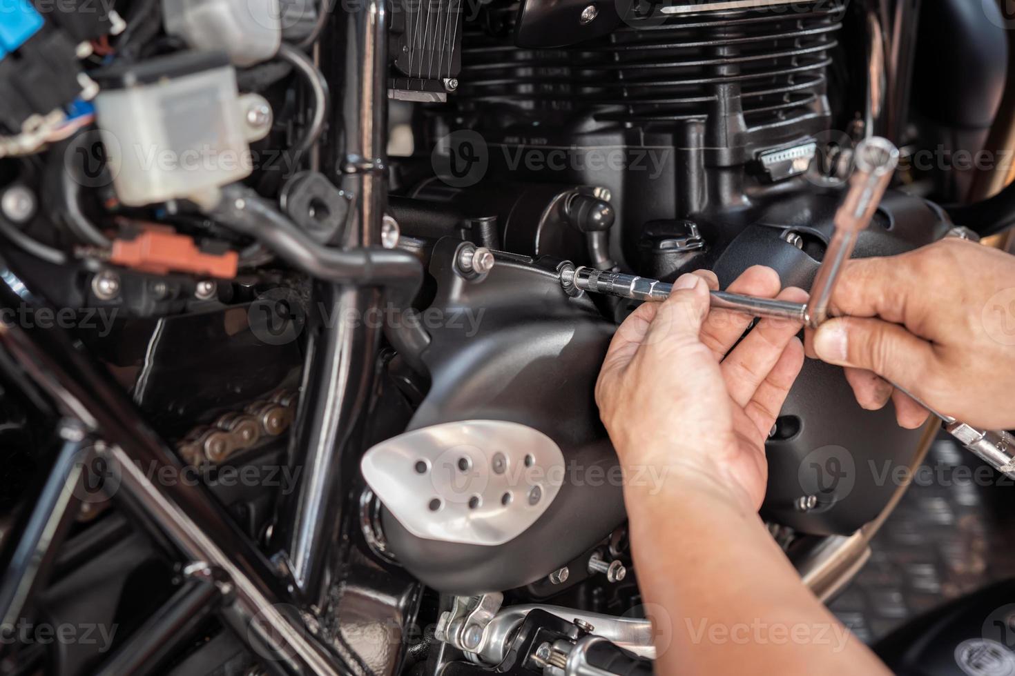 mekaniker använder sig av en y form rycka till ta bort främre kedjehjul omslag på motorcykel, arbetssätt i garage .underhåll och reparera motorcykel begrepp .selektiv fokus foto