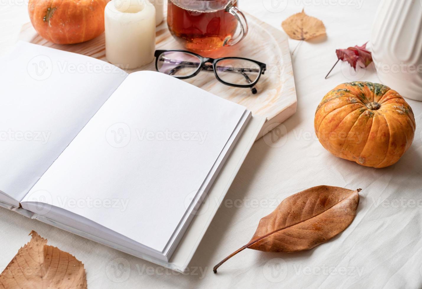 vit tom bok med höst löv, glasögon och ljus på vit tabell , attrapp design foto