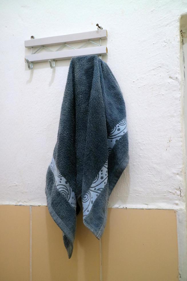 mörkblå våt handduk hängde på badrumsväggen foto