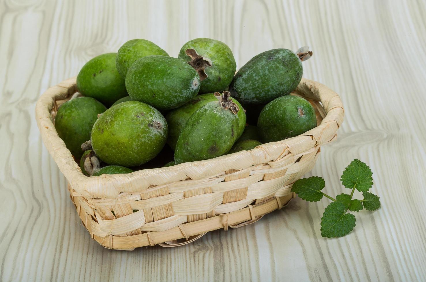 feijoa i en korg på trä- bakgrund foto