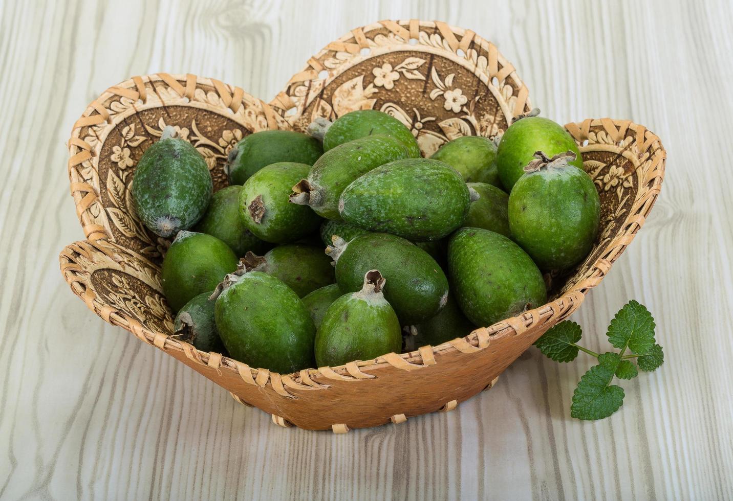 feijoa i en korg på trä- bakgrund foto