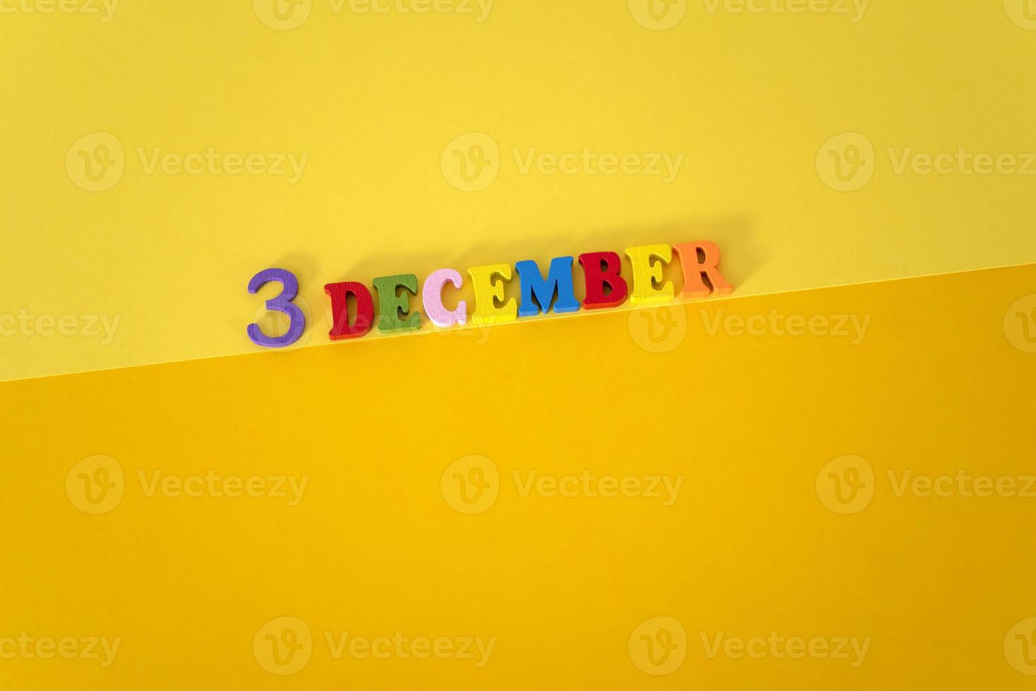 december 3 på en gul och papper bakgrund med trä- och flerfärgad brev med Plats för text. foto