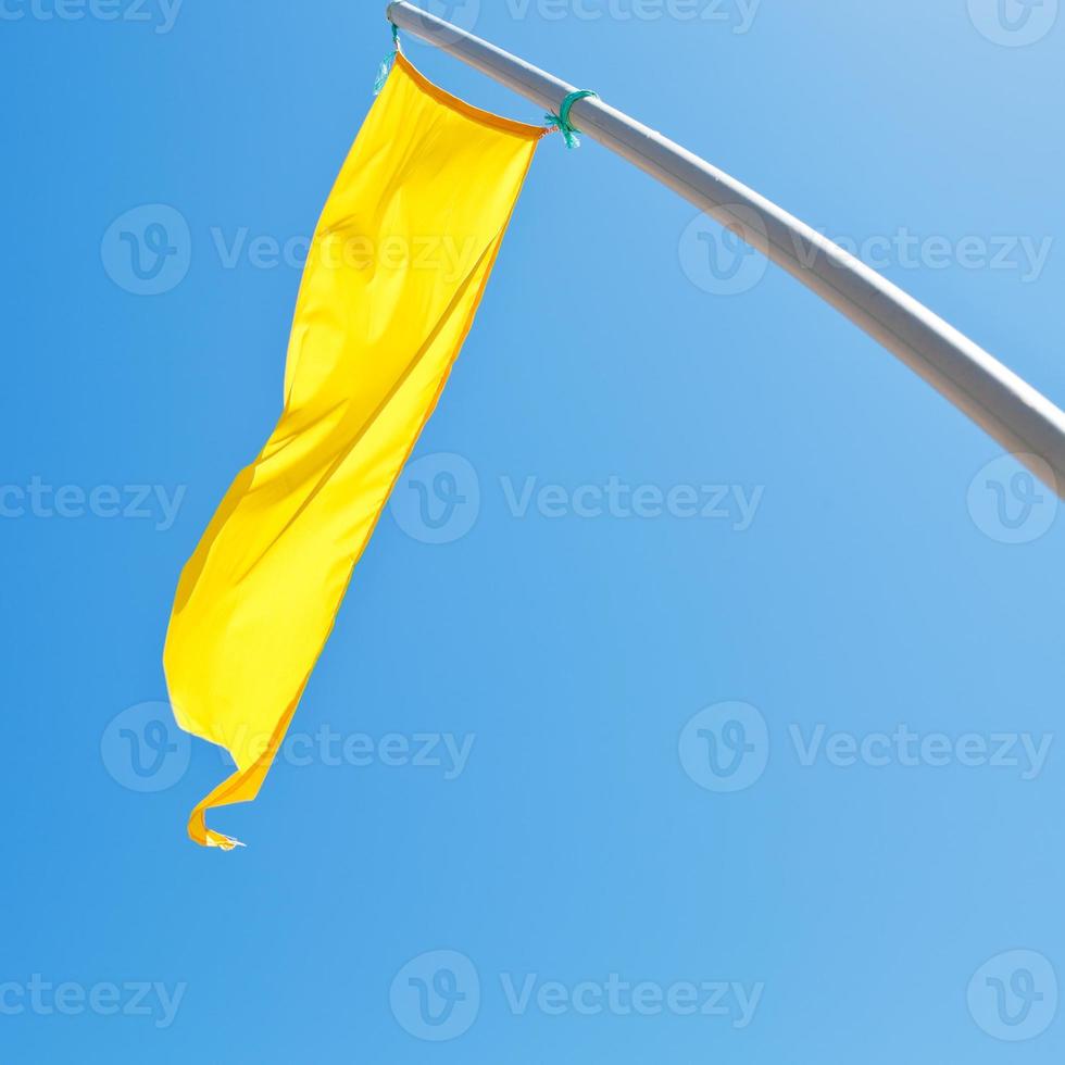 varning tecken - gul flagga med blå himmel foto