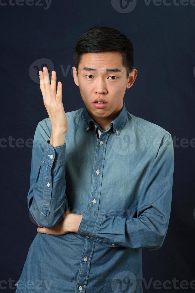 missnöjd ung asiatisk man som gör en gest med en hand foto