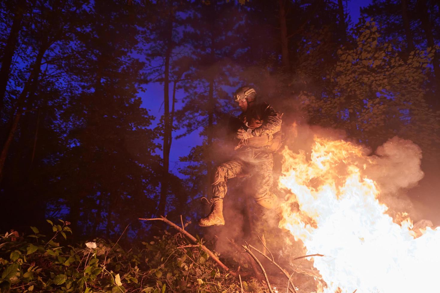 soldat i verkan på natt Hoppar över brand foto