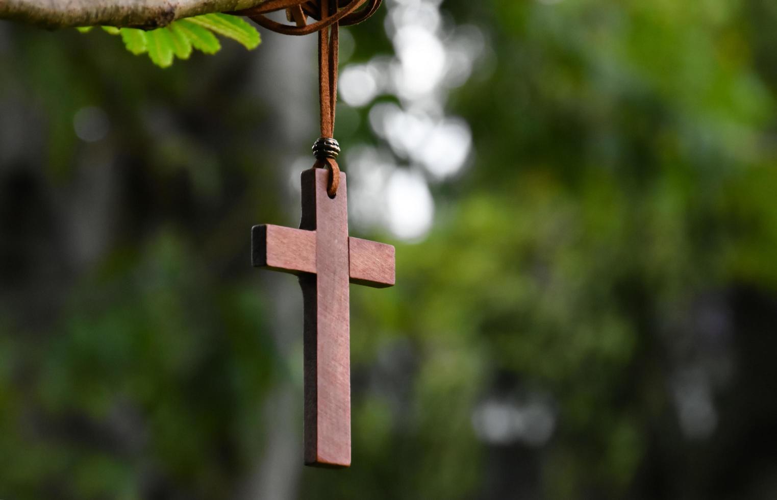 trä- korsa hängande på träd gren, mjuk och selektiv fokus, naturlig bokeh träd bakgrund, begrepp för hoppas, kärlek, förlåtelse och tro i Jesus runt om de värld. foto