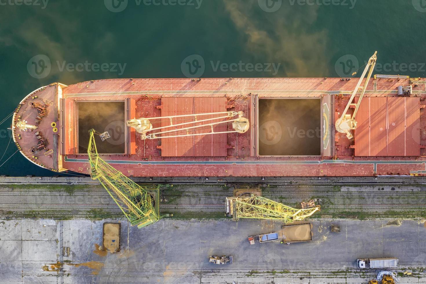 topp se från Drönare av en stor fartyg läser in spannmål för exportera. vatten transport foto
