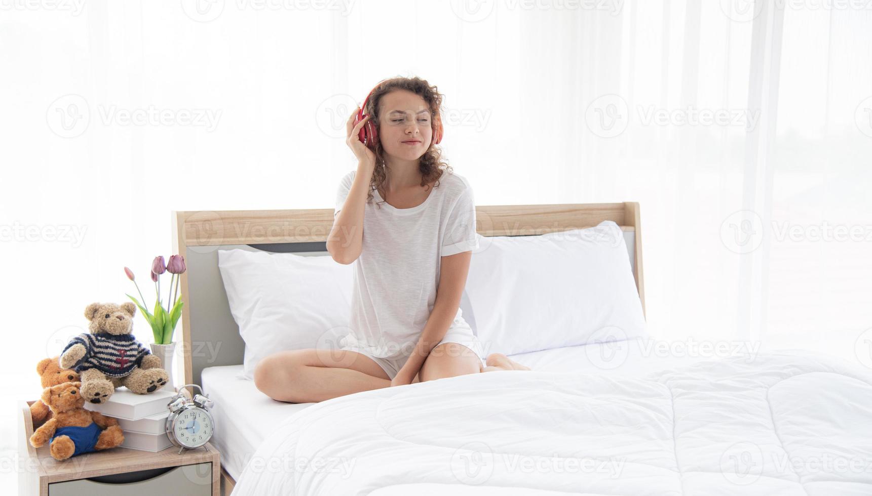 caucasian skön kvinna med tråkig ansikte eller olycklig Sammanträde på de bekväm dubbel- säng i de modern eller minimal interiör sovrum design dekorerad med , vit strö och trä- möbel foto