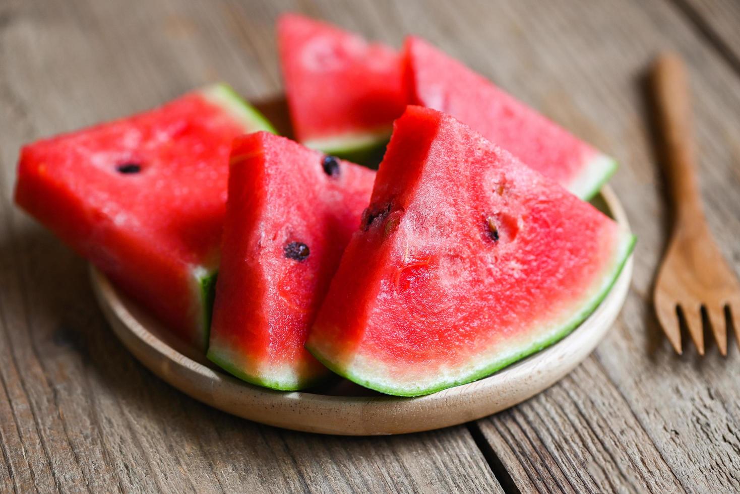 ljuv vattenmelon skivor bitar färsk vattenmelon tropisk sommar frukt, vattenmelon skiva på tallrik trä- bakgrund foto