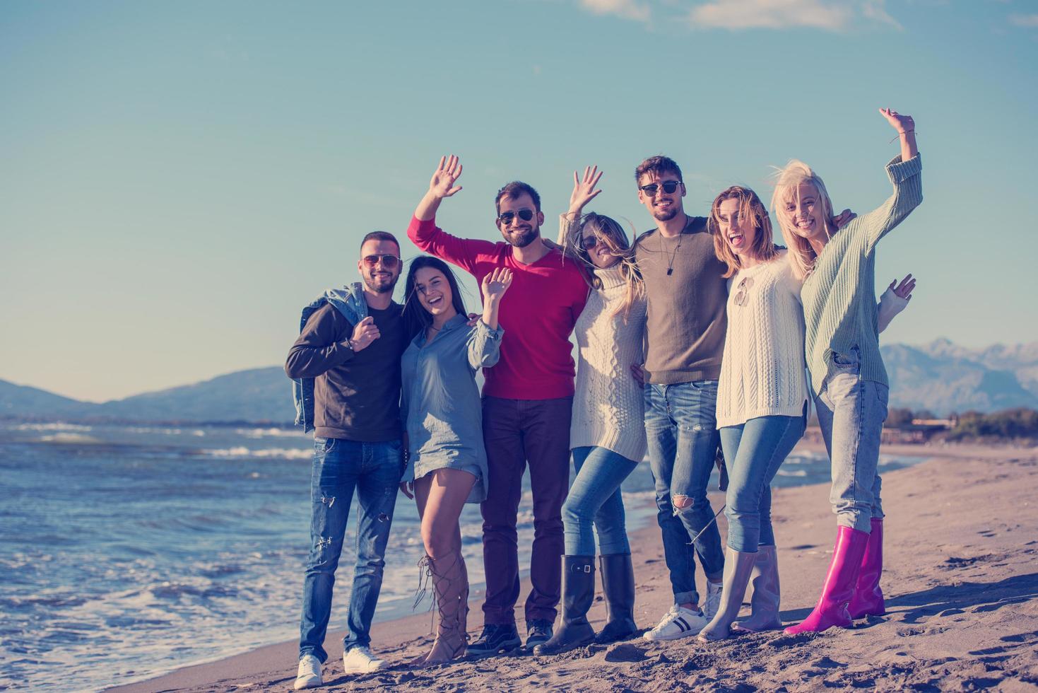 porträtt av vänner har roligt på strand under höst dag foto