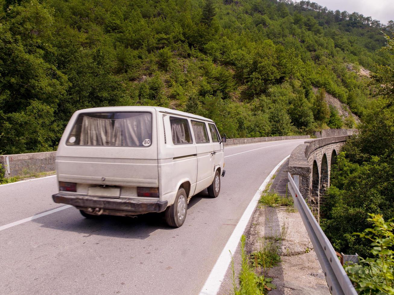 gammal vit skåpbil på asfalt väg i skön landsbygden foto