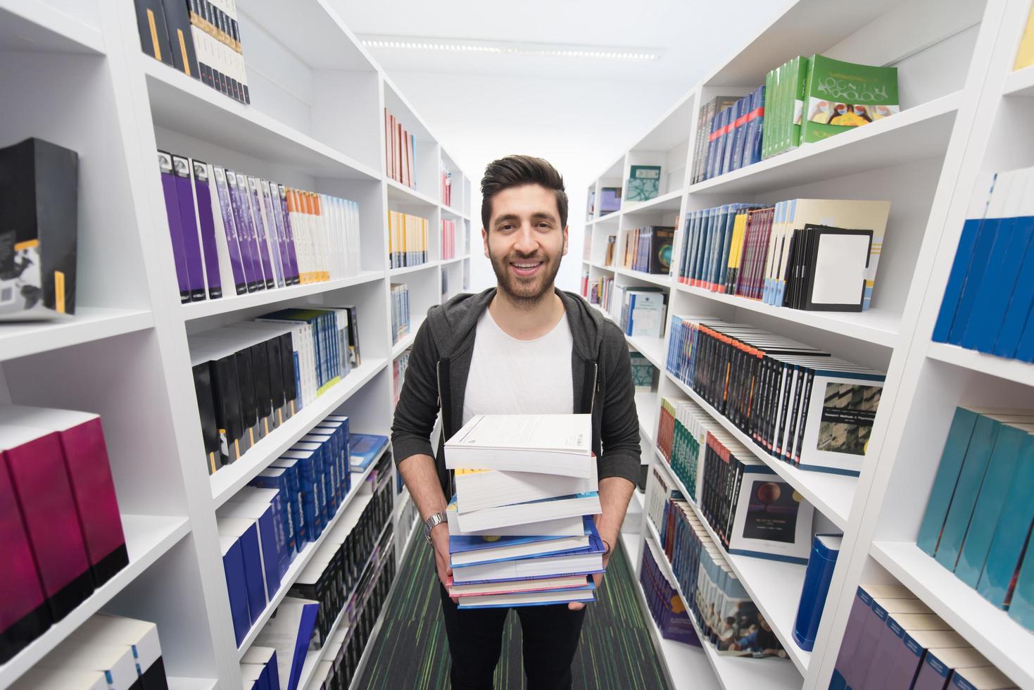 studerande innehav massa av böcker i skola bibliotek foto