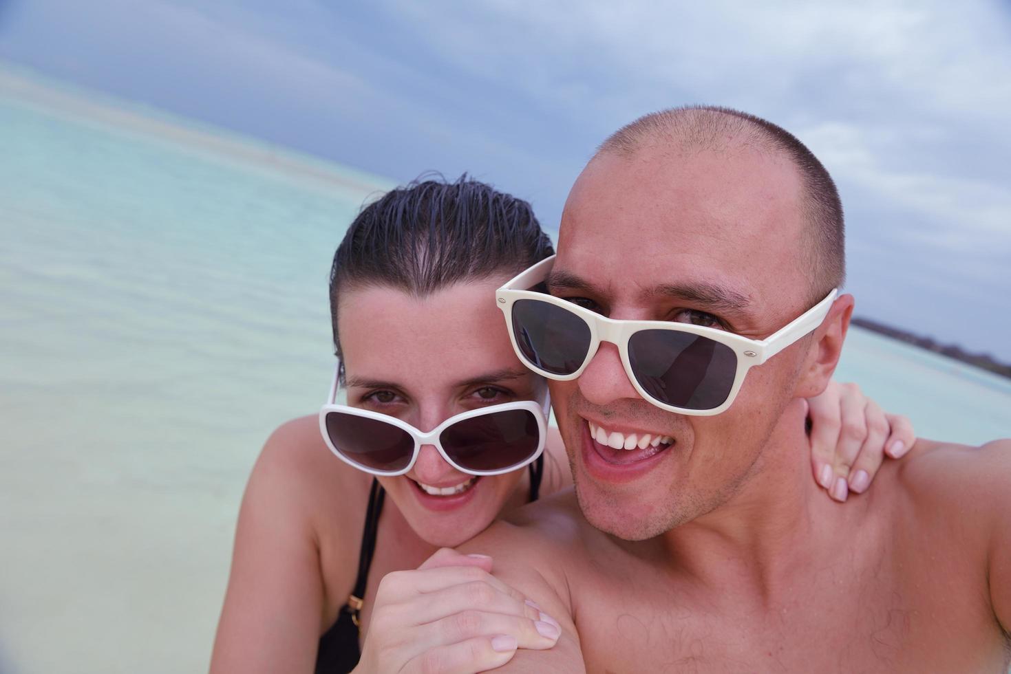 Lycklig ung par på sommar semester ha roligt och koppla av på strand foto