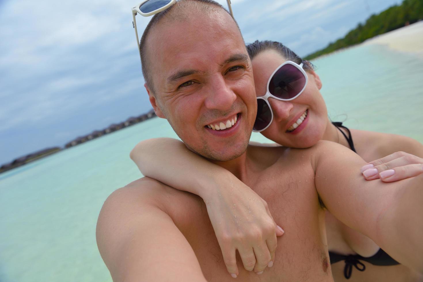 Lycklig ung par på sommar semester ha roligt och koppla av på strand foto