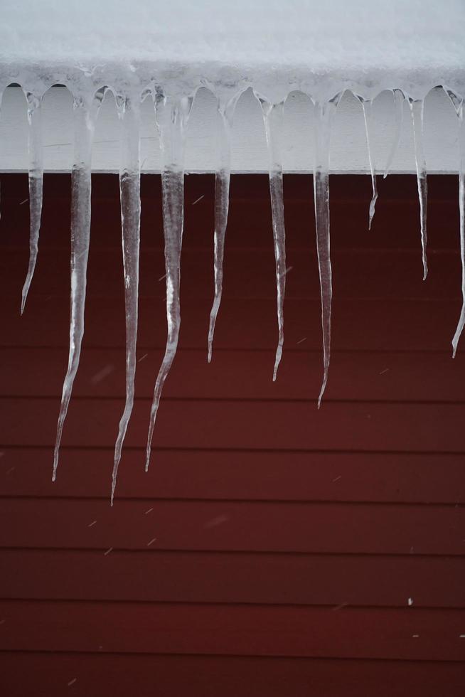 istappar på taket av ett rött hus i norge foto