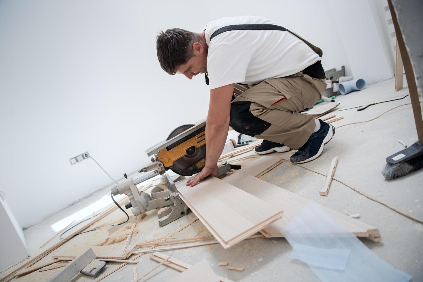 man skärande laminera golv planka med elektrisk cirkulär fick syn på foto