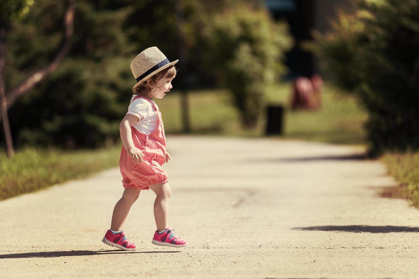 liten flicka springer i sommarparken foto