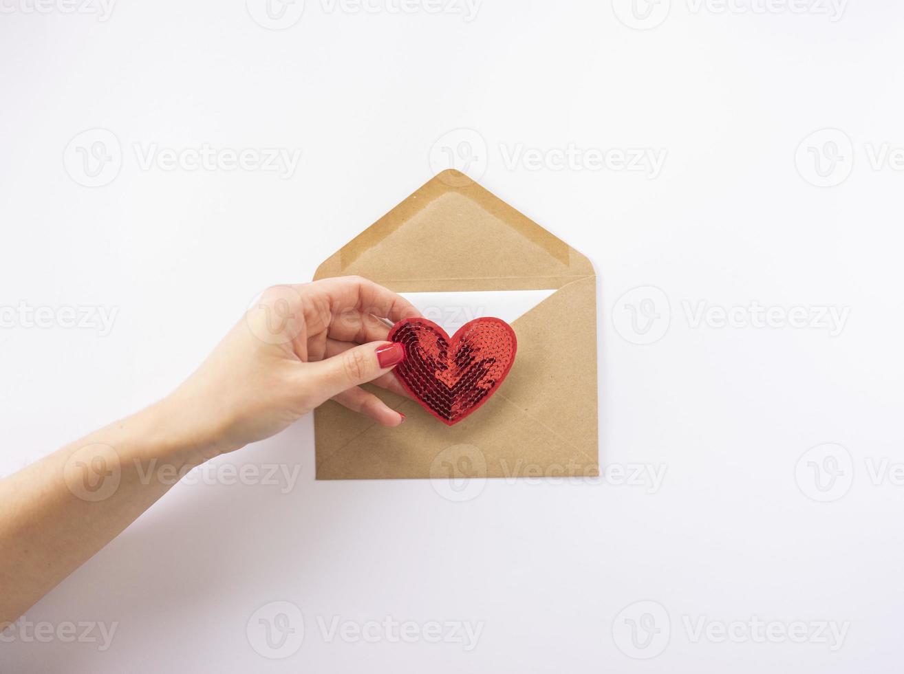 en kvinna innehar en röd hjärta i henne hand redo till skicka den som en posta kort för valentines dag foto