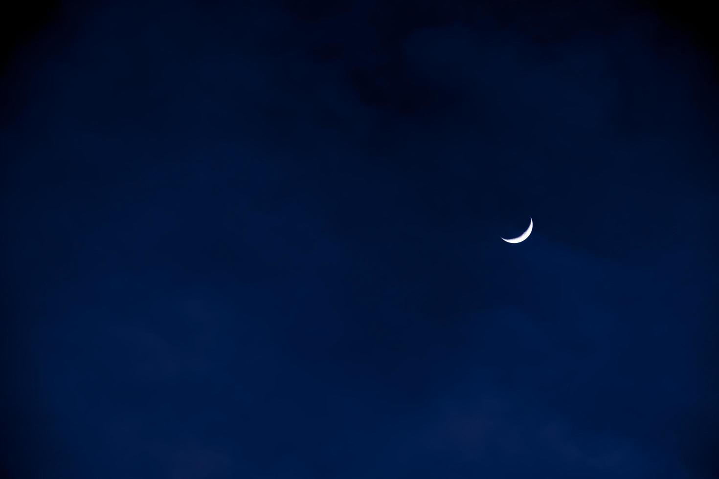 halv måne i de tidigt kväll på mörk blå himmel, foto