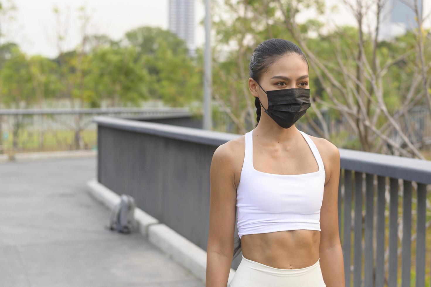 ung fitness kvinna i sportkläder tar ansiktsmask i medan träning i stadsparken, hälsa och livsstil. foto