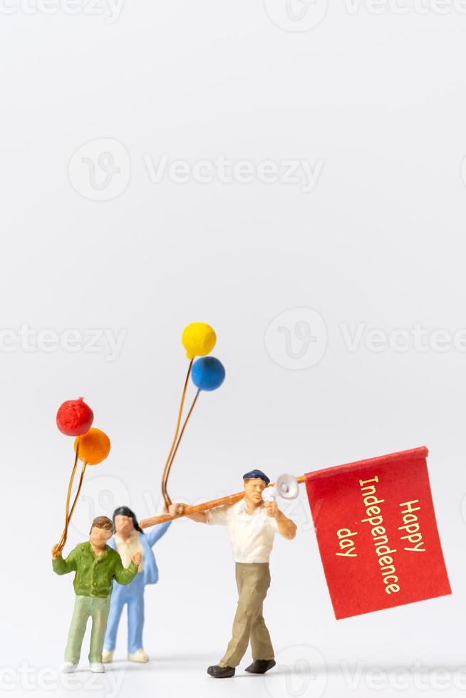 miniatyr människor som håller flaggor med ordet glad självständighetsdagen foto