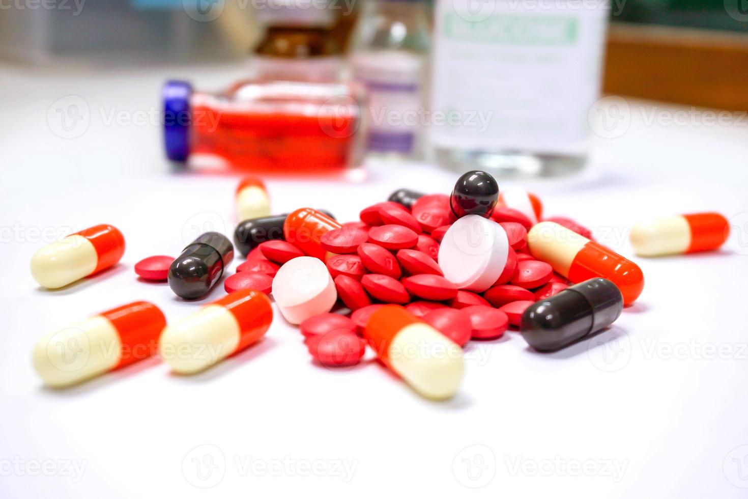 närbild av röda piller mediciner och kapsel plats på vitt bord med ampul suddig bakgrund. foto