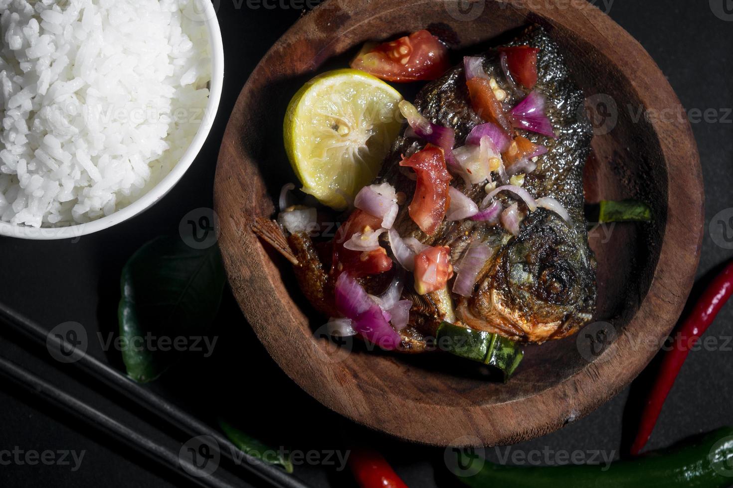 kryddig stekt fiskmeny med risskål på svart bakgrund. asiatisk matfotografering. bra för restaurangmeny och affisch foto